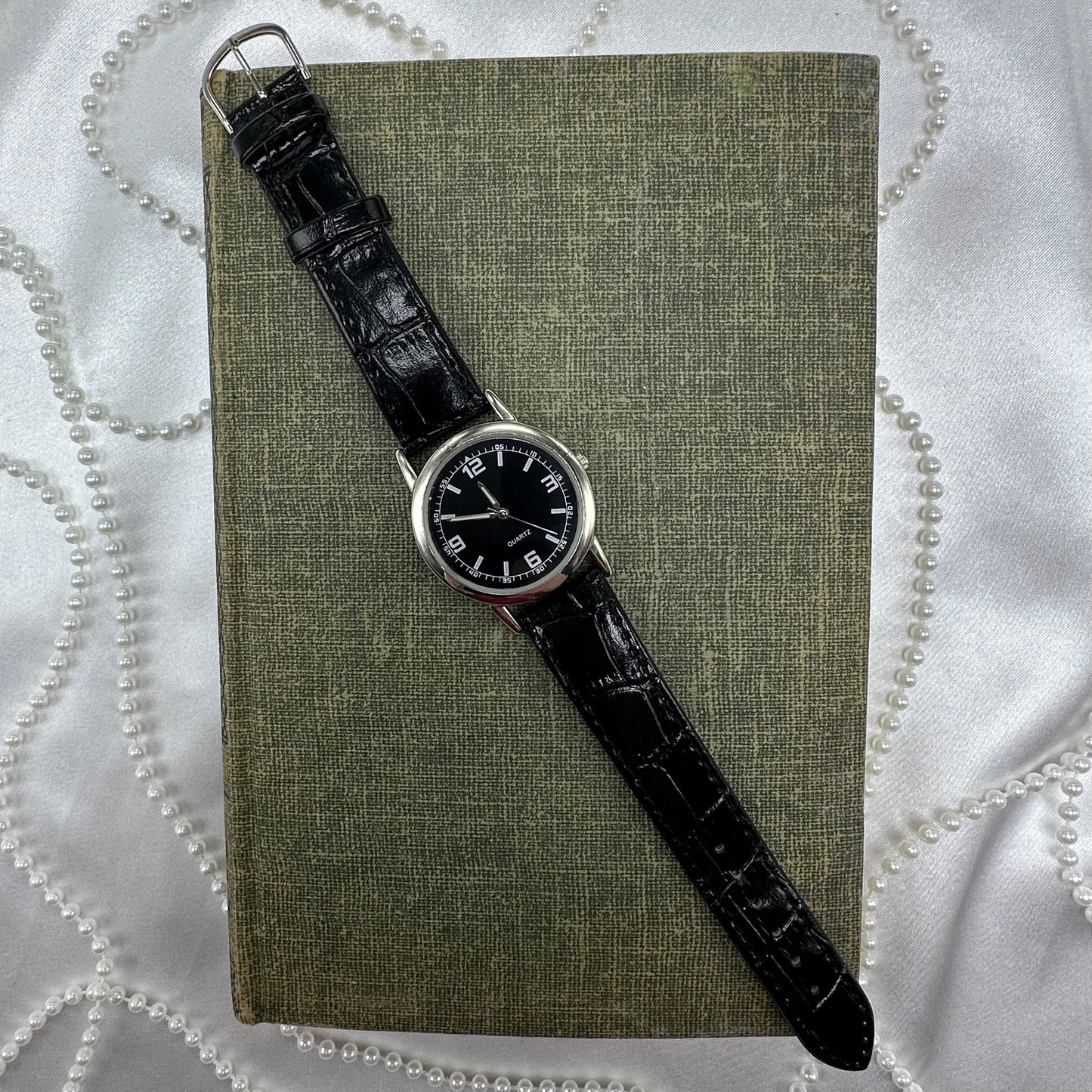 Silver tone watch with black dial and quartz movement.