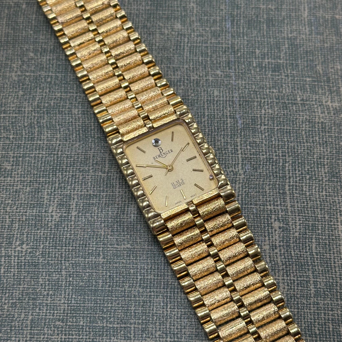 Vintage gold tone chunky tank Berenger watch with rectangle dial and textured clasp band.