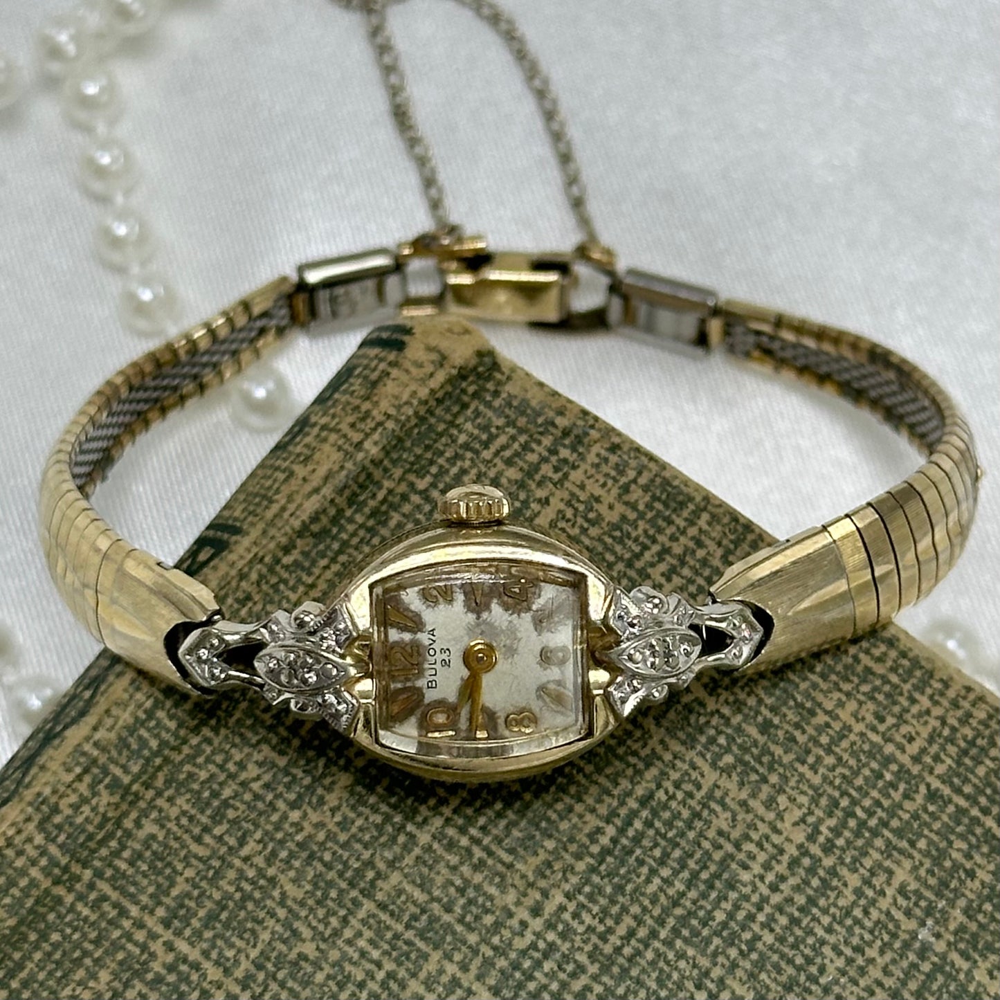 Dainty vintage 10k rolled gold plated Bulova 23 jewels manual winding cocktail watch from the 1960's with ornate diamanté dial and detailed clasp band.