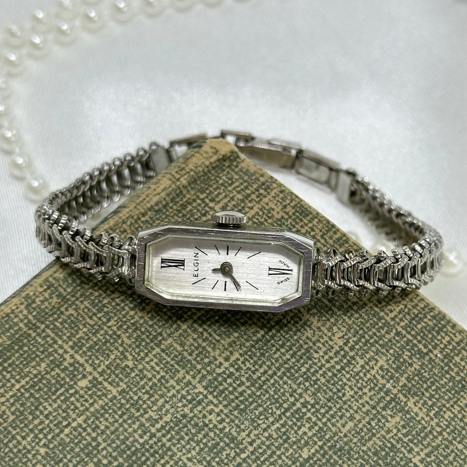 Dainty vintage silver tone manual winding Elgin watch with unique chain band and rectangle dial.