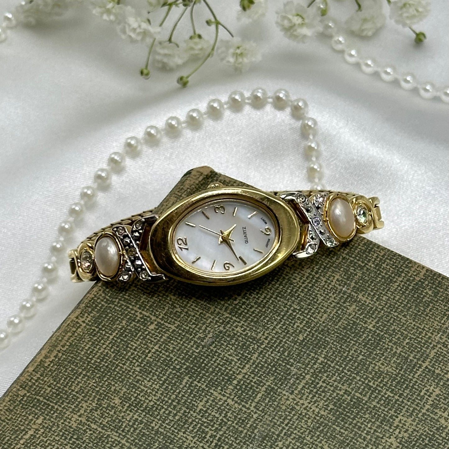 Gold tone diamanté and pearl Avon watch with quartz movement and stretchable band. Dial is mother of pearl.