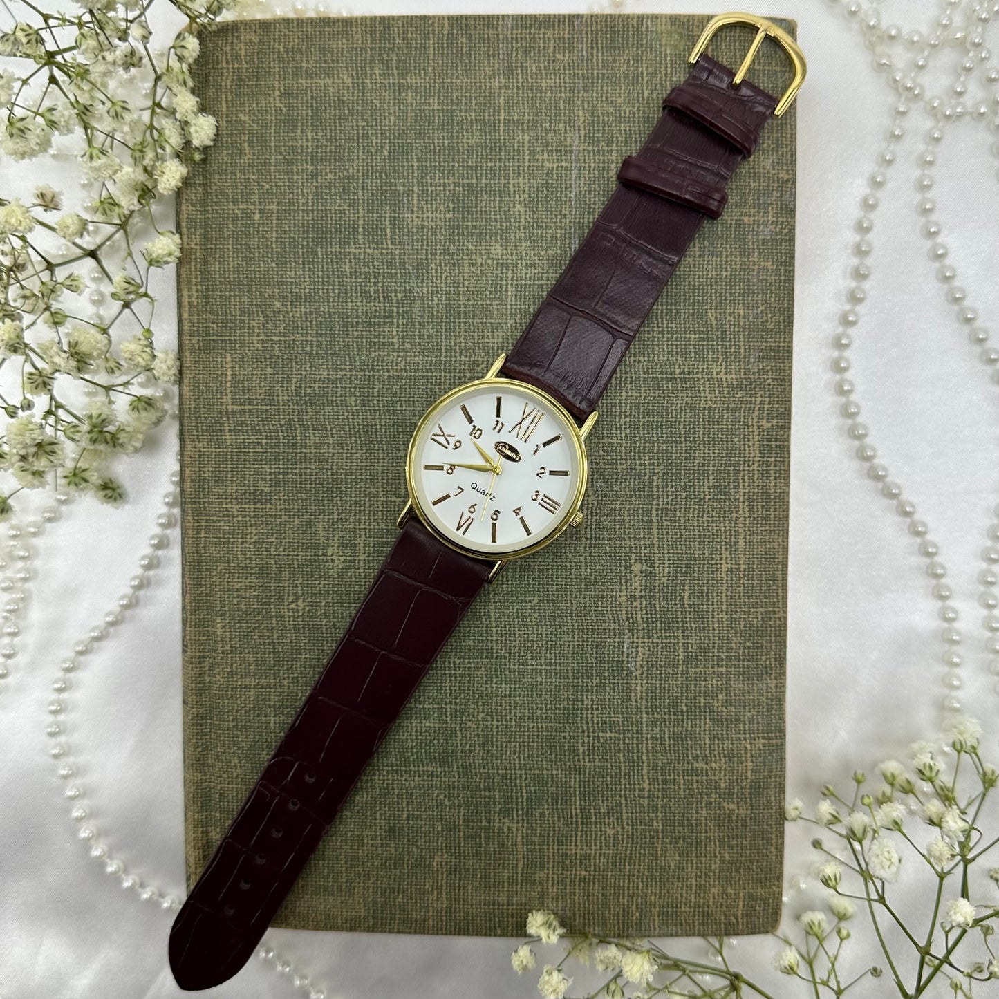 Gold tone round dial Cambridge watch with quartz movement and faux leather band.