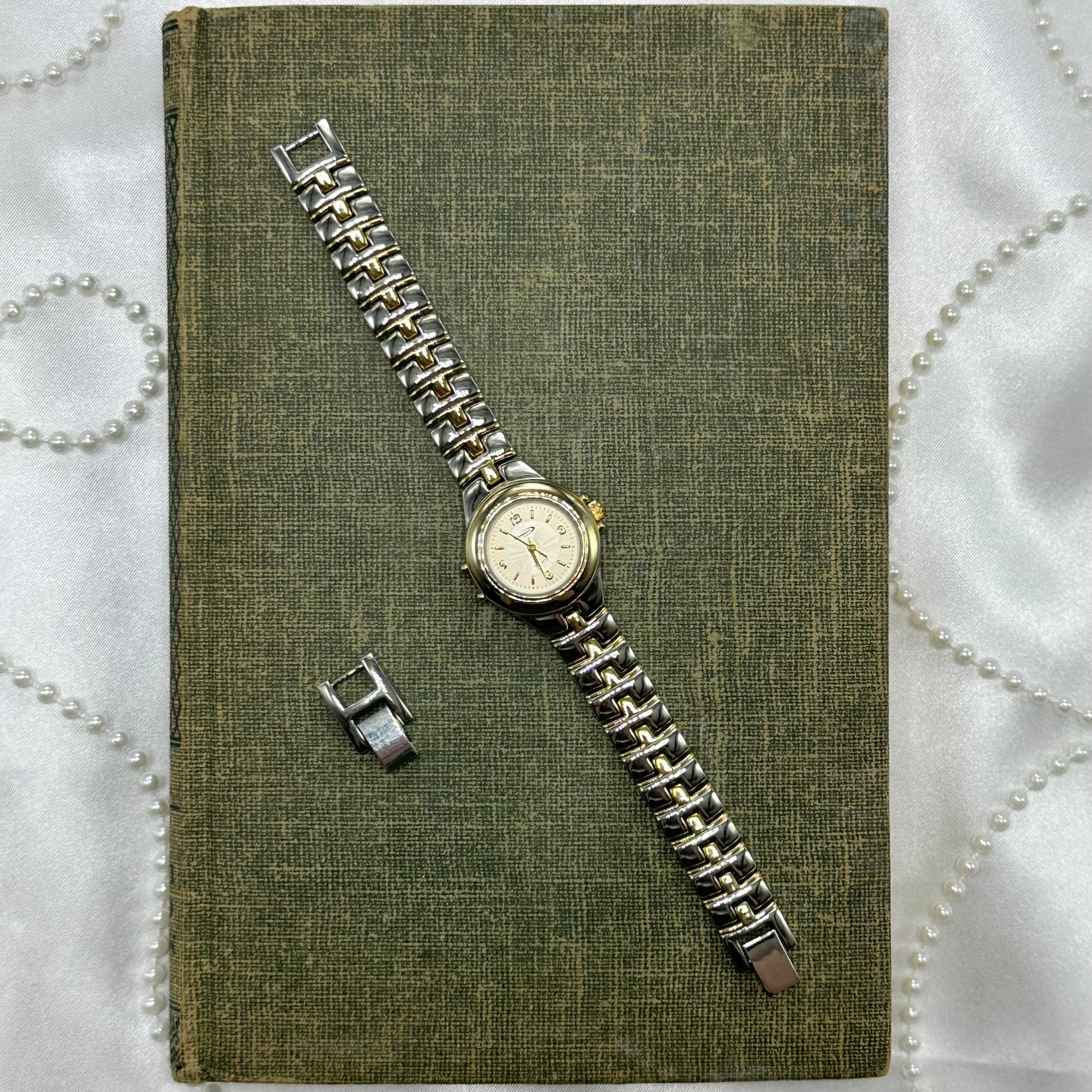 Silver and gold tone Nelsonic watch with two-tone clasp band and quartz movement.