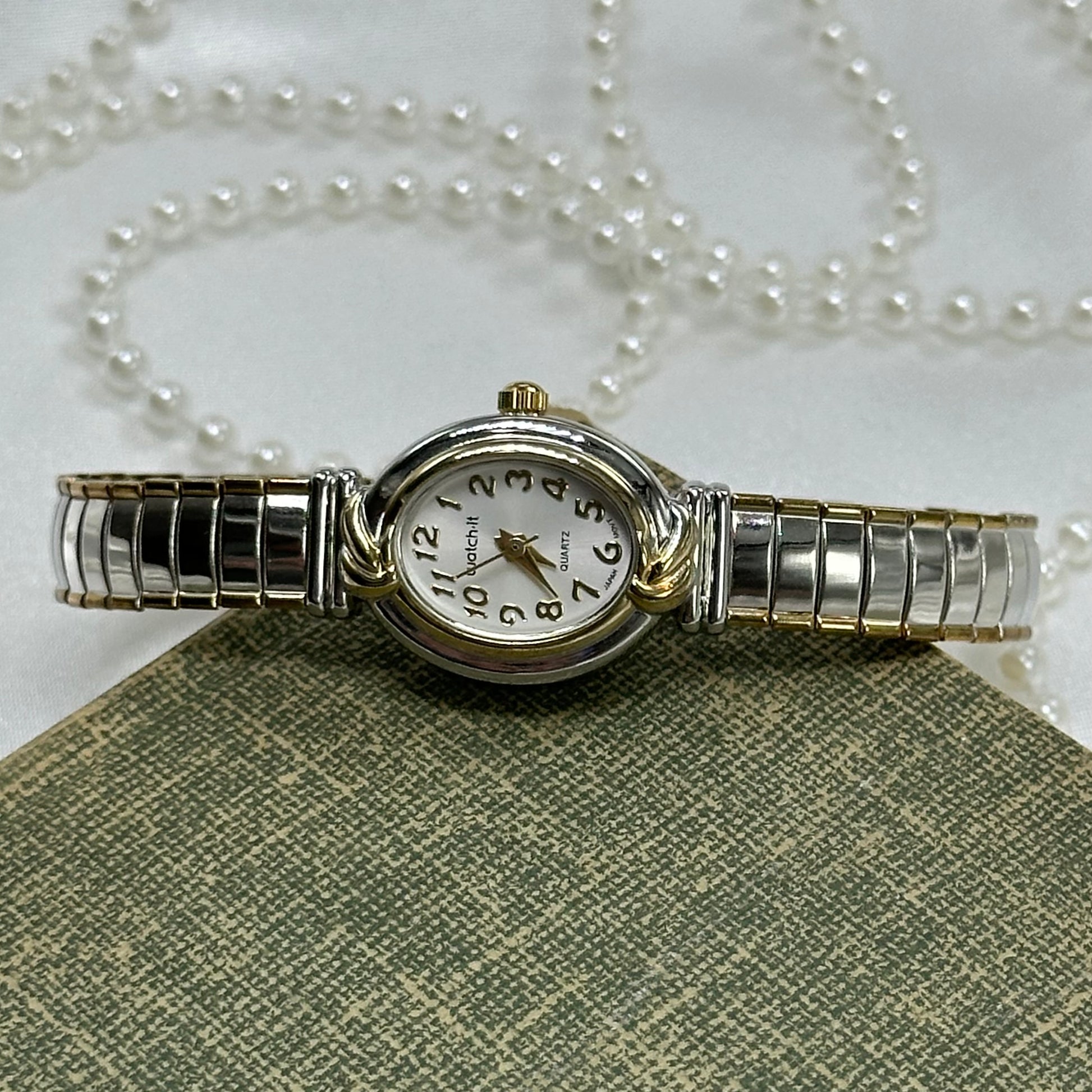 Silver and gold tone Watch-It watch with stretchable band and quartz movement.