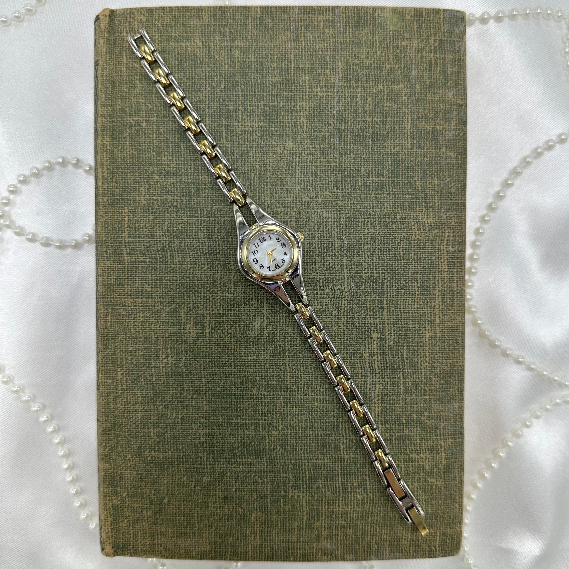 Silver and gold tone round dial watch with two-tone band and quartz movement. Dial is mother of pearl.
