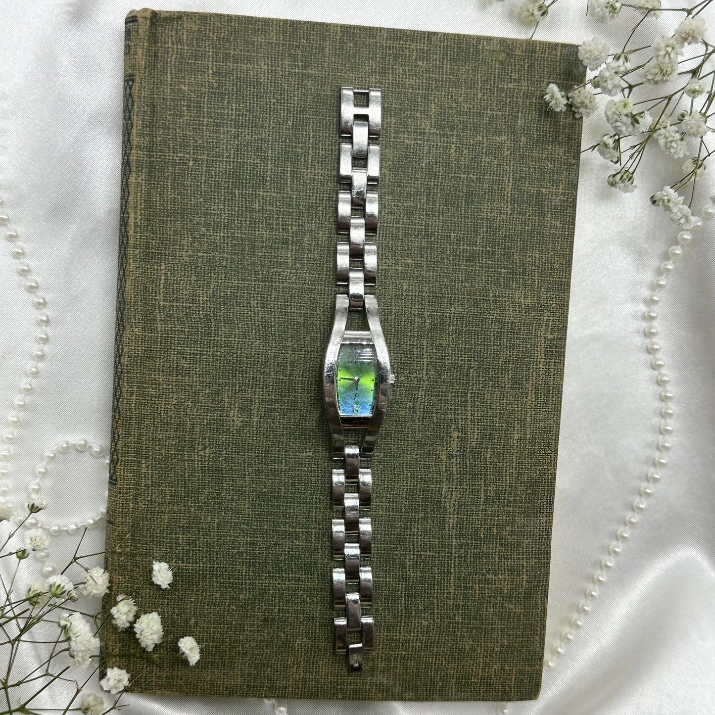 Silver tone Fossil watch with blue and green iridescent dial and clasp band.