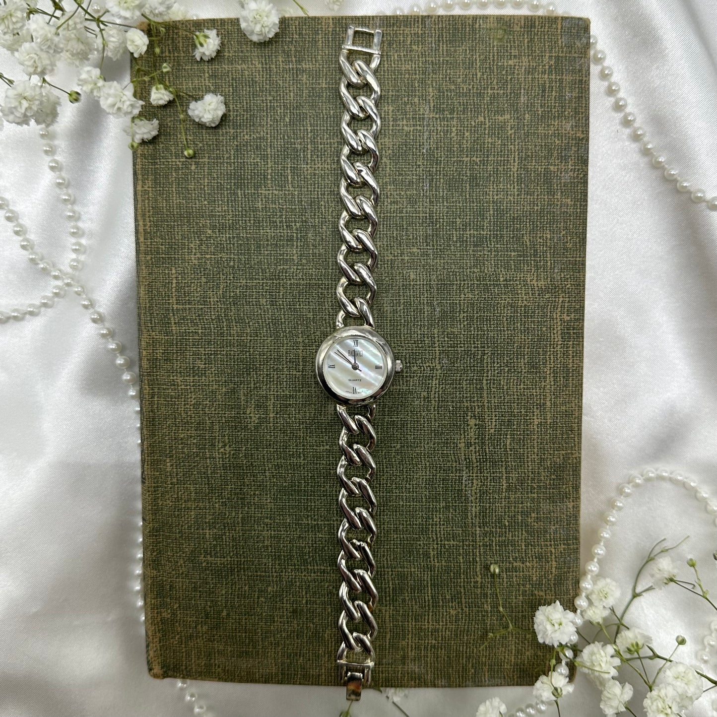 Silver tone watch with quartz movement and chain band.