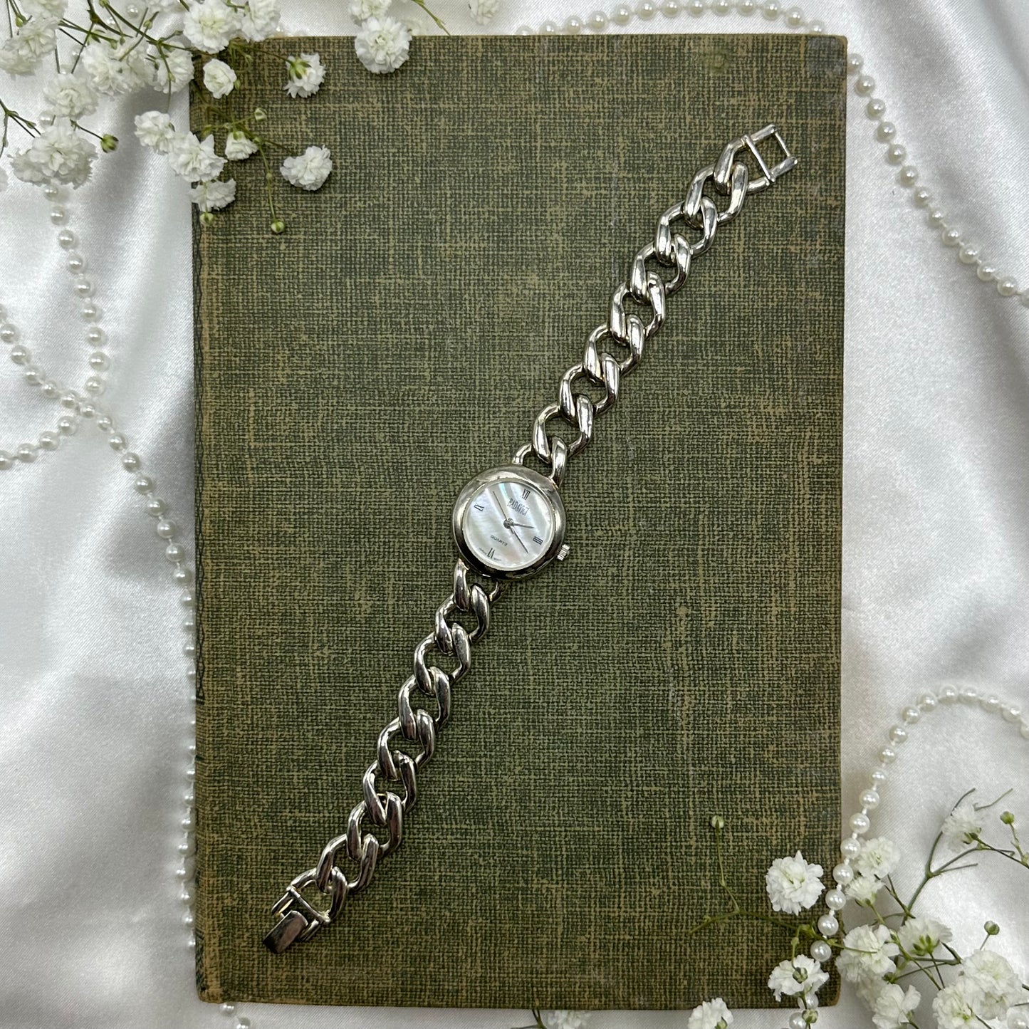 Silver tone watch with quartz movement and chain band. Dial is mother of pearl.