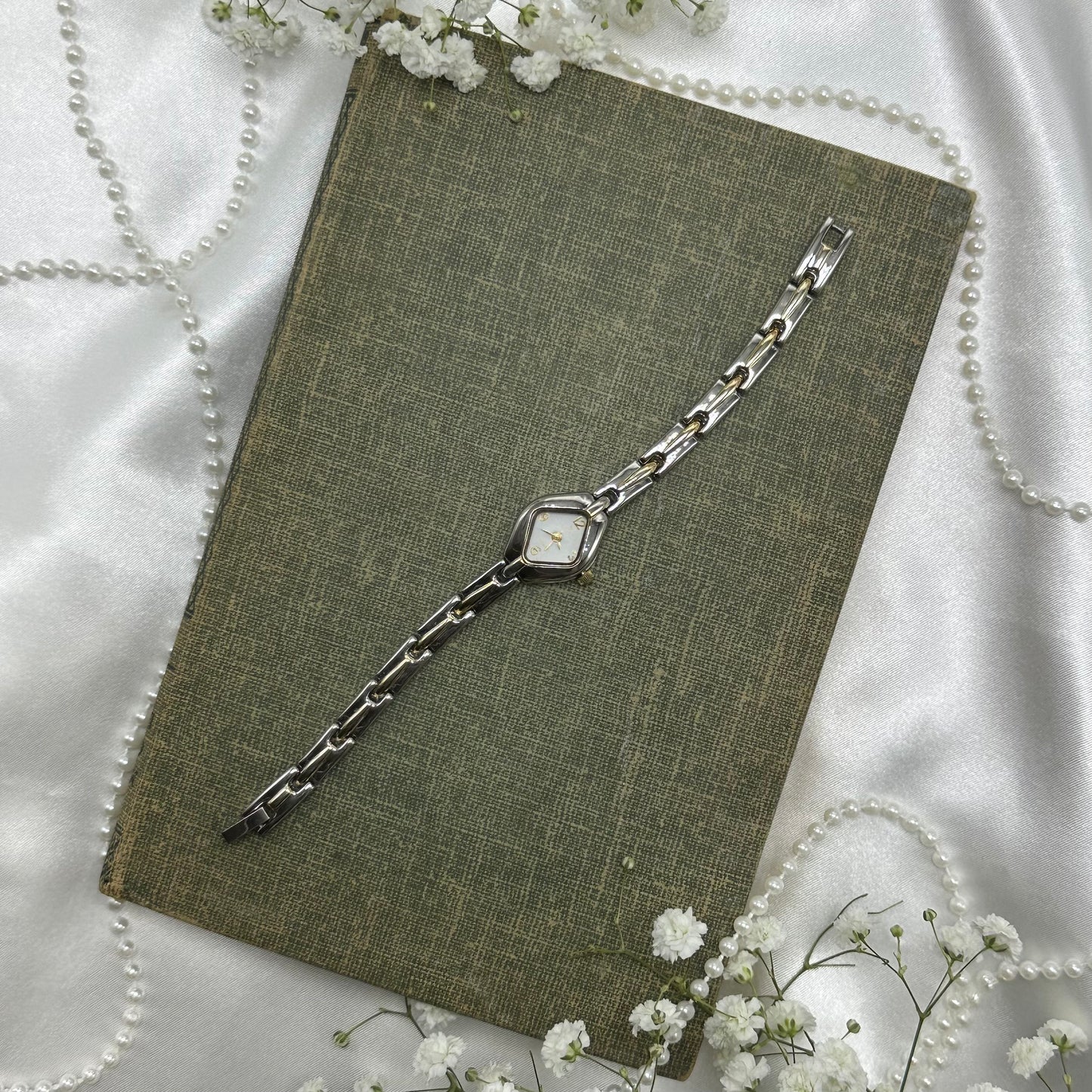 Slim silver and gold tone watch with clasp band.