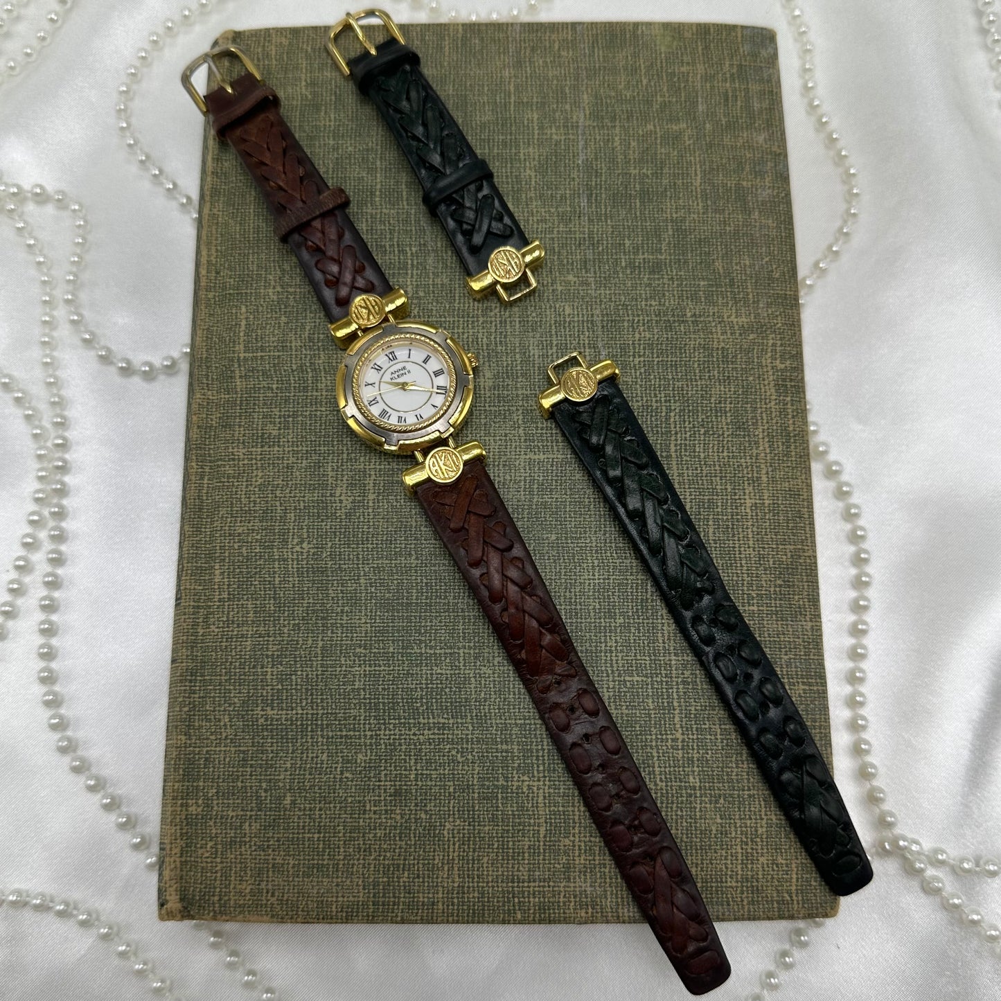 Vintage Anne Klein gold tone round dial watch with interchangeable black and brown leather braided bands. Dial screws off to swap bands easily.