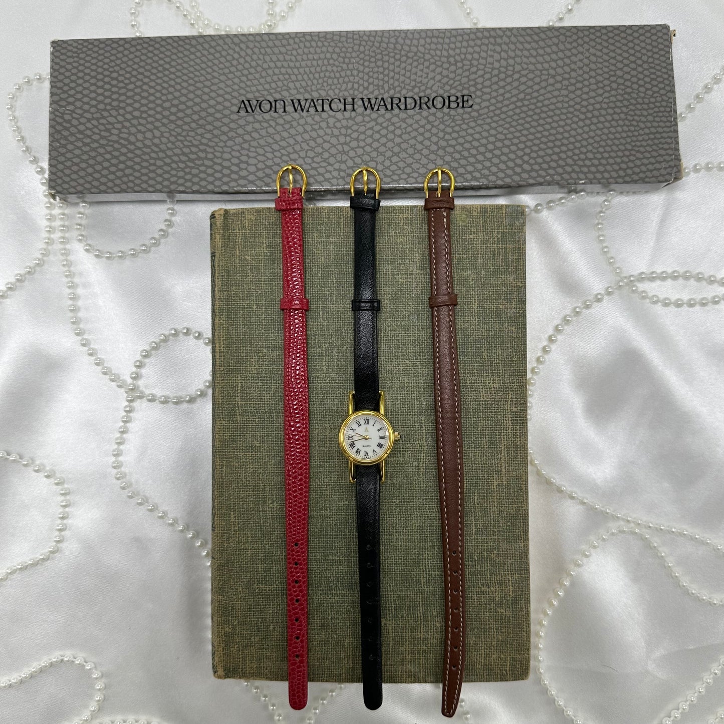 Vintage gold tone Avon watch set. Watch crown is a black jewel. Set includes 3 interchangeable bands (red, black, & brown) and original packaging.