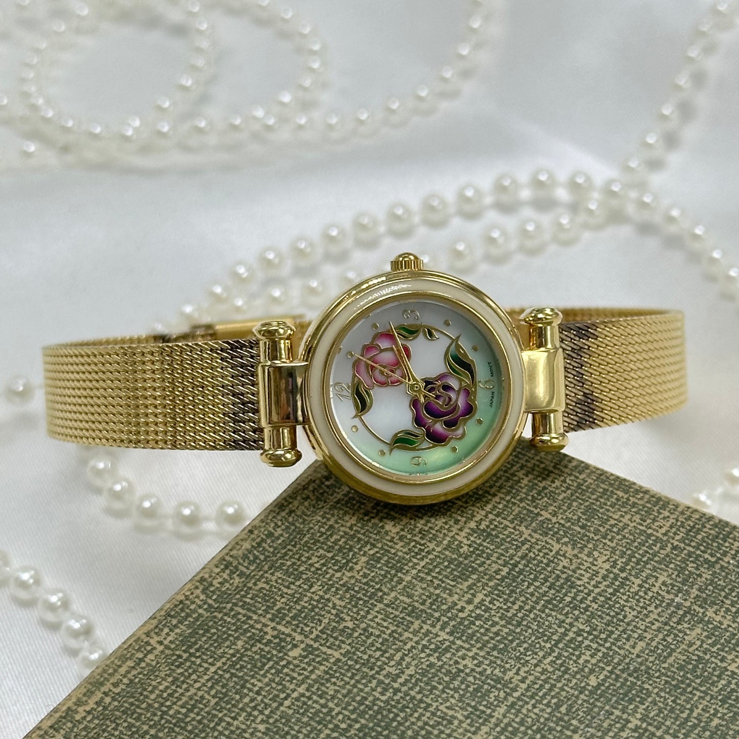 Vintage gold tone Avon watch with round flower dial and quartz movement.