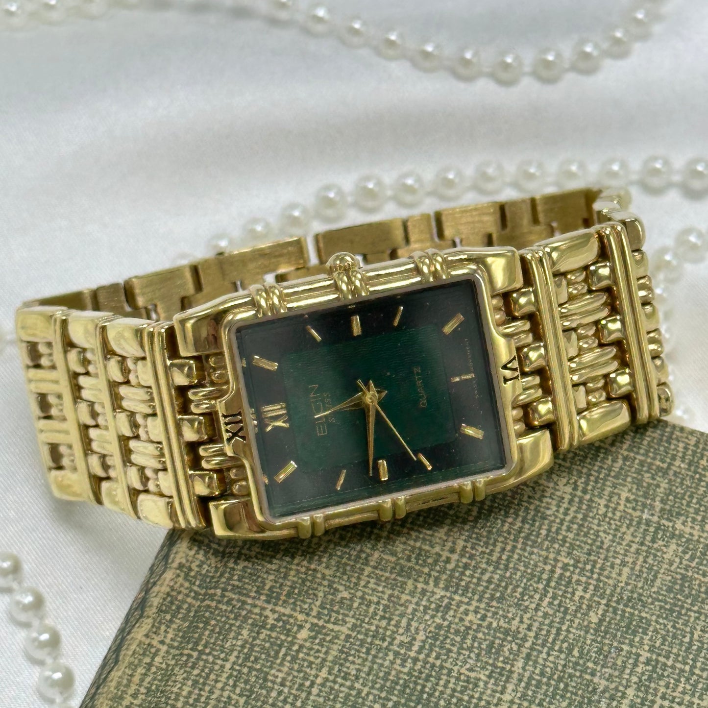 Vintage gold tone Elgin Swiss tank watch with rectangular green dial and thick metal band. Back is engraved.