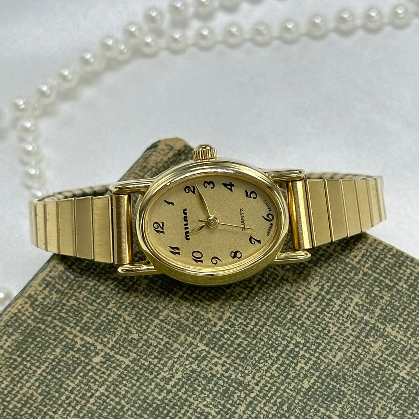 Vintage gold tone Milan watch with stretchable band and quartz movement.