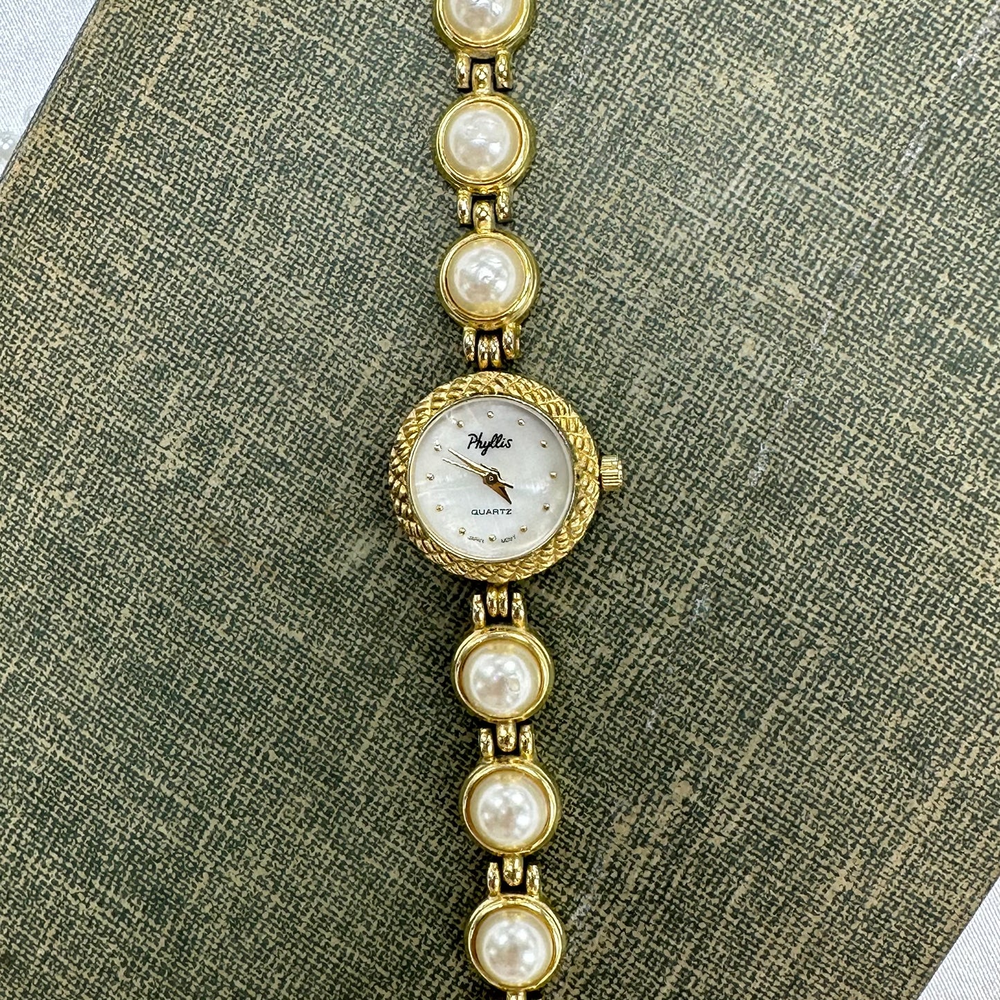 Vintage gold tone Phyllis watch with faux pearl band and mother of pearl dial. One of the pearls is missing.