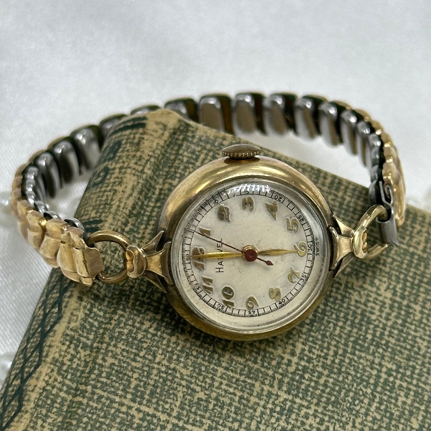 Vintage gold tone round dial manual winding Harvel watch with stretchable band and red second hand.