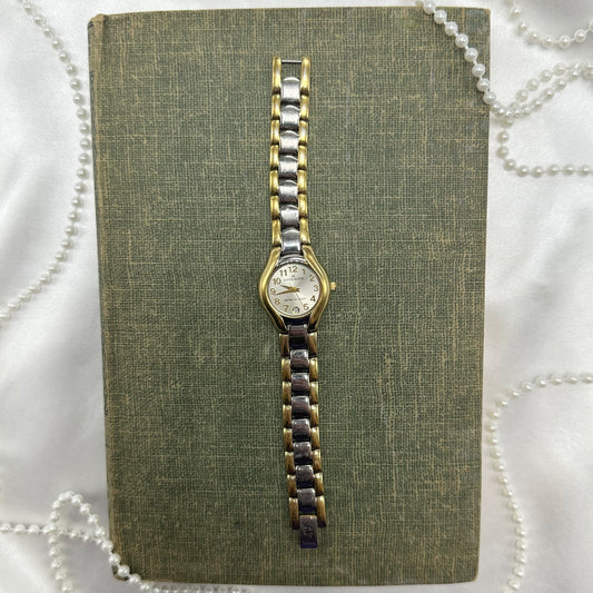 Vintage silver and gold tone Anne Klein watch with date display and clasp band.