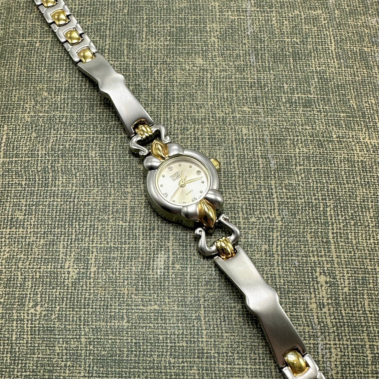 Vintage silver and gold tone Faded Glory watch with round dial and unique band.