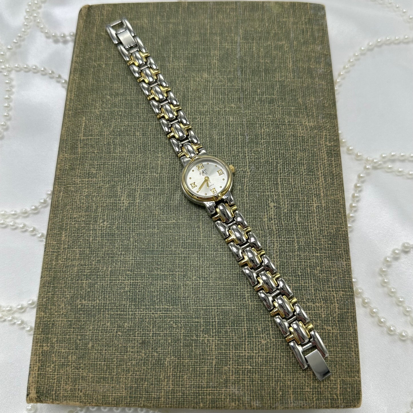 Vintage silver and gold tone LA-X watch with round dial and gold roman numeral markers.