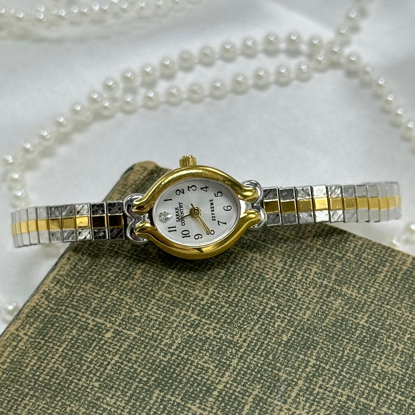 Vintage silver and gold tone Sarah Coventry watch with dainty oval dial and two-tone stretchable band.