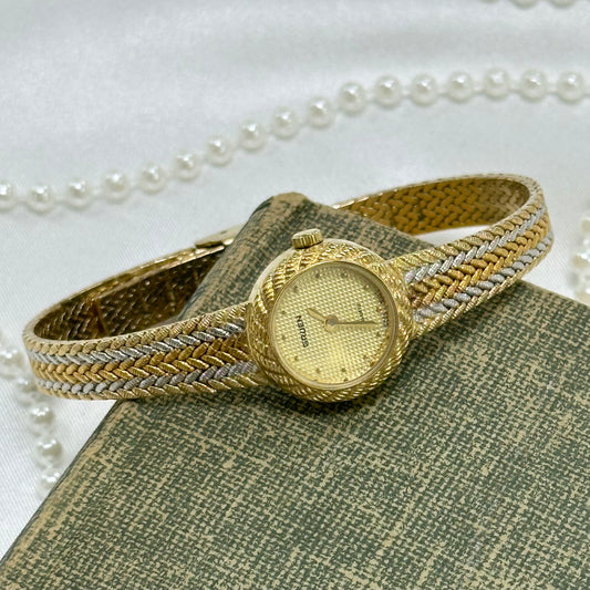 Vintage silver, gold, and bronze tone Gruen watch with tri-tone braided band and dainty round dial.