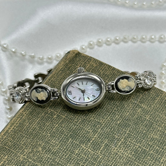 Vintage silver tone watch with black cameos and crystal stones. Dial is mother of pearl