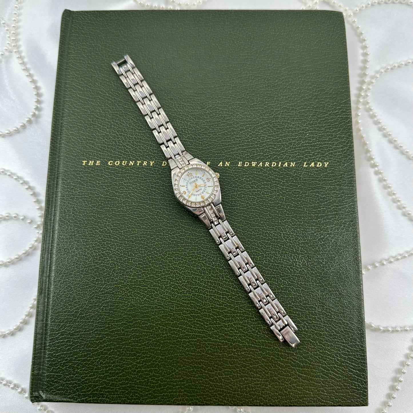 Silver and gold tone Studio Time watch with diamanté mother of pearl dial and two-tone metal clasp band.