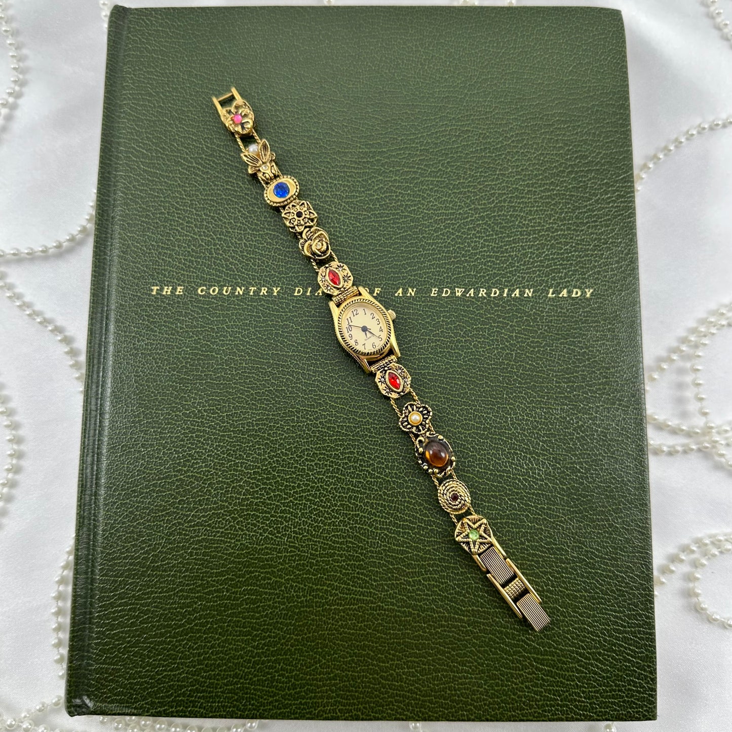 Rare vintage gold tone Avon watch with oval dial and multicolor slide charm band.