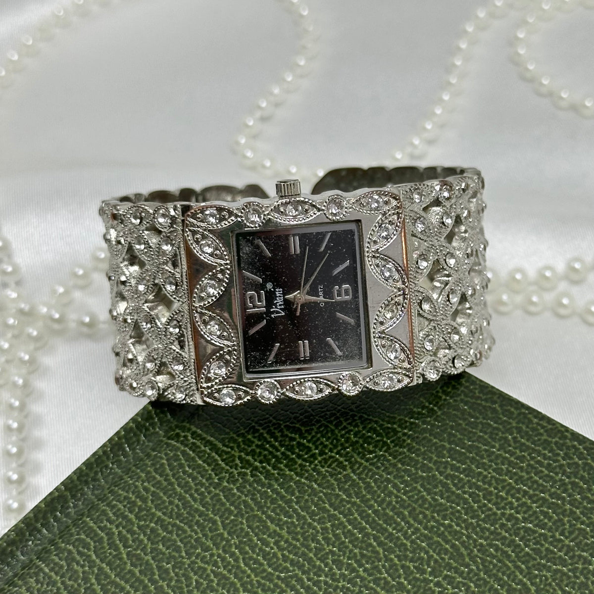 Vintage silver tone cuff watch with square black dial.