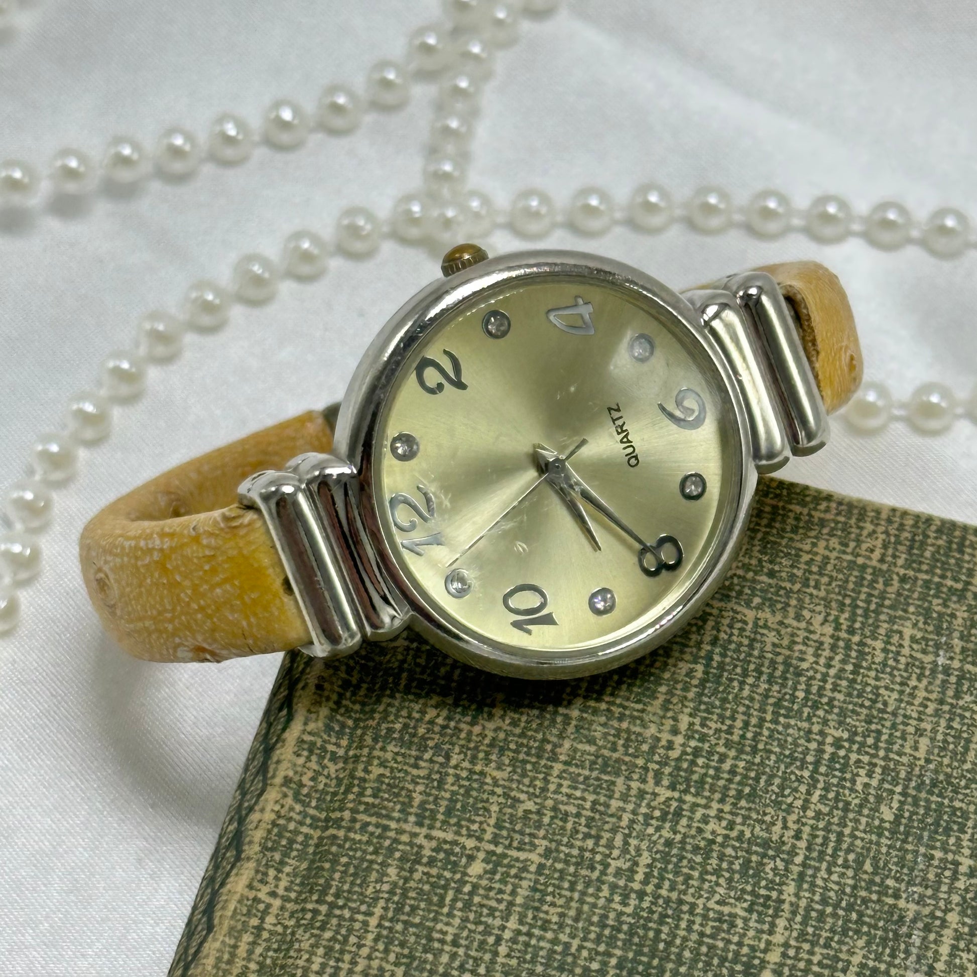 Silver tone round dial cuff watch with tan leather patterned band and quartz movement.