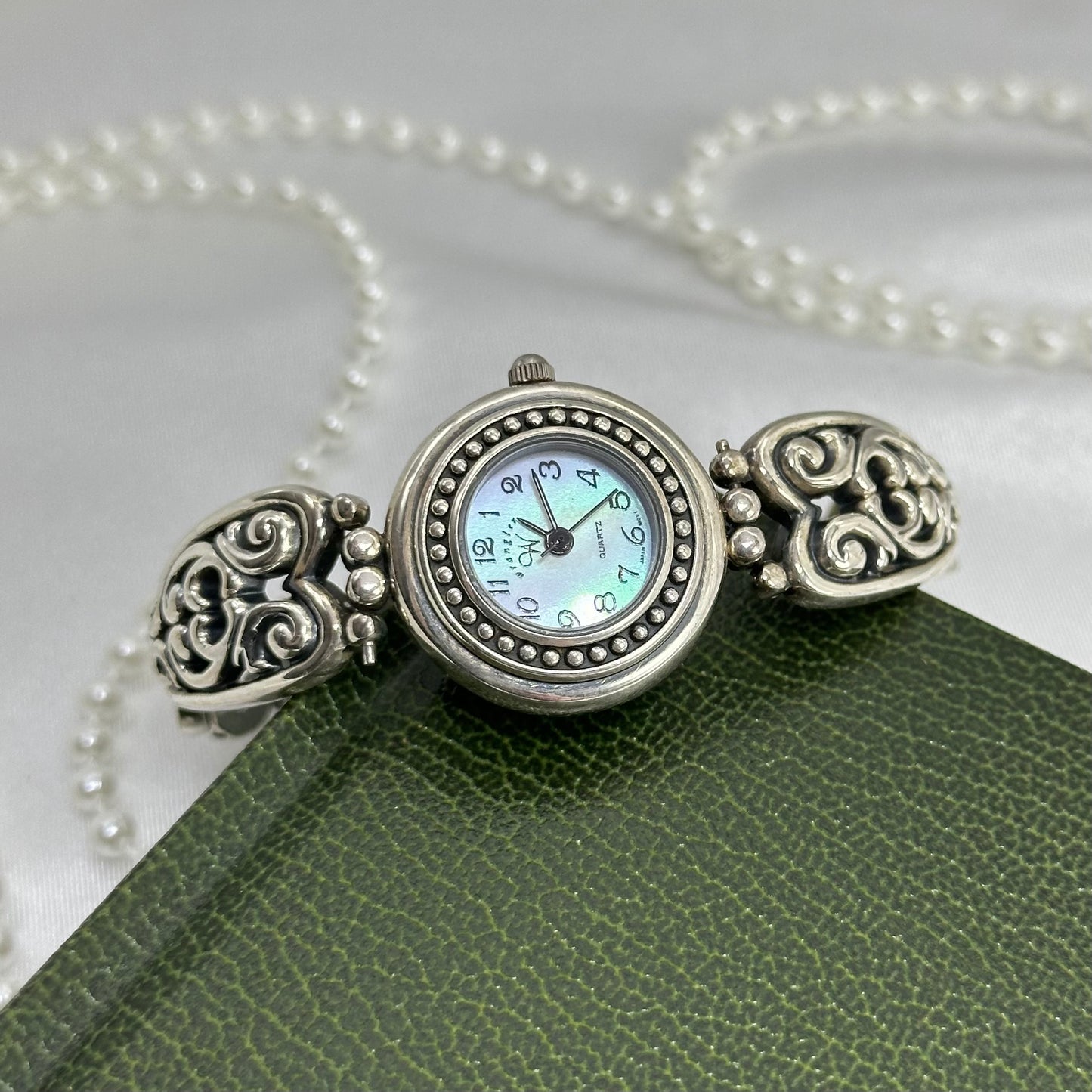Silver tone Wrangler watch with round mother of pearl dial and filigree bracelet band.