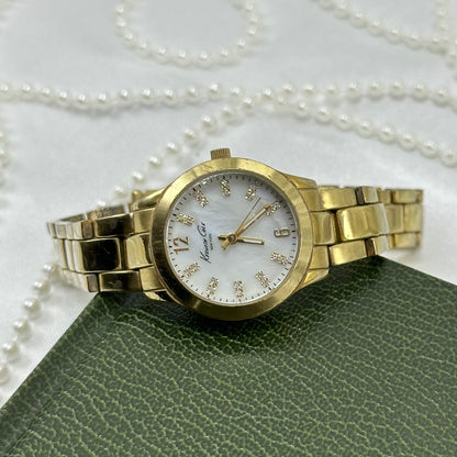 Vintage gold tone Kenneth Cole tank watch with round mother of pearl dial and double locking fold over clasp.