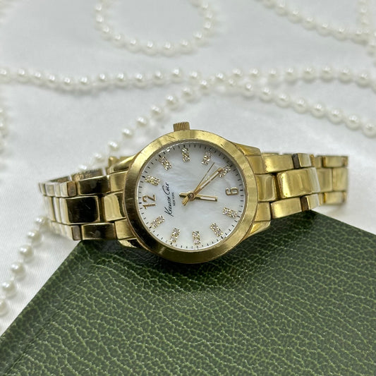 Vintage gold tone Kenneth Cole tank watch with round mother of pearl dial and double locking fold over clasp.