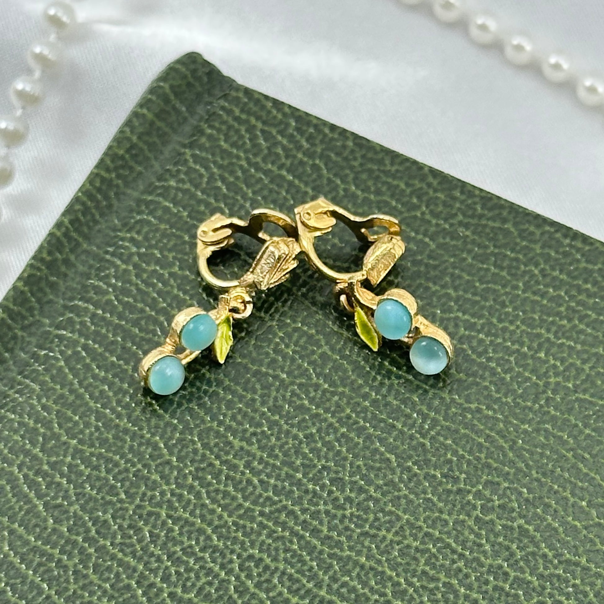 Vintage dangle gold tone clip on fruit and leaf motifs earrings with light blue cabochon stones.
