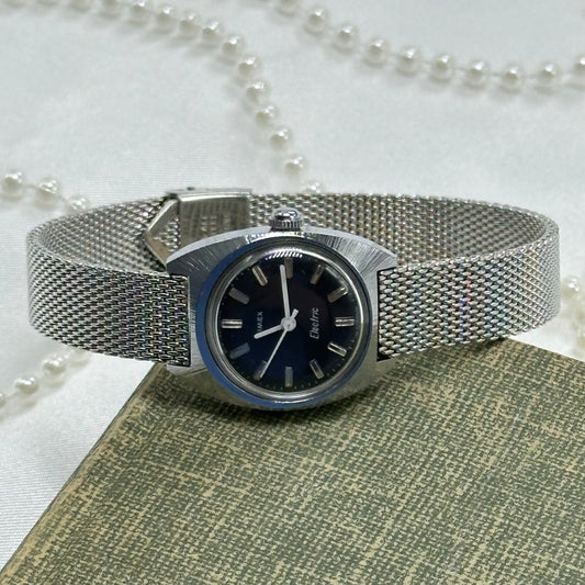 Vintage silver tone Timex Electric watch with navy blue dial and mesh band.