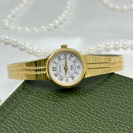 Vintage slender gold tone Armitron watch with round dial and metal clasp band.