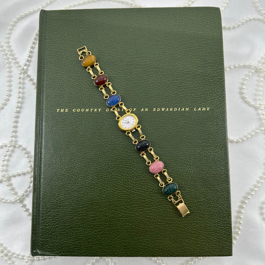 Vintage gold tone Belle watch with dainty oval dial and multicolor scarab band.