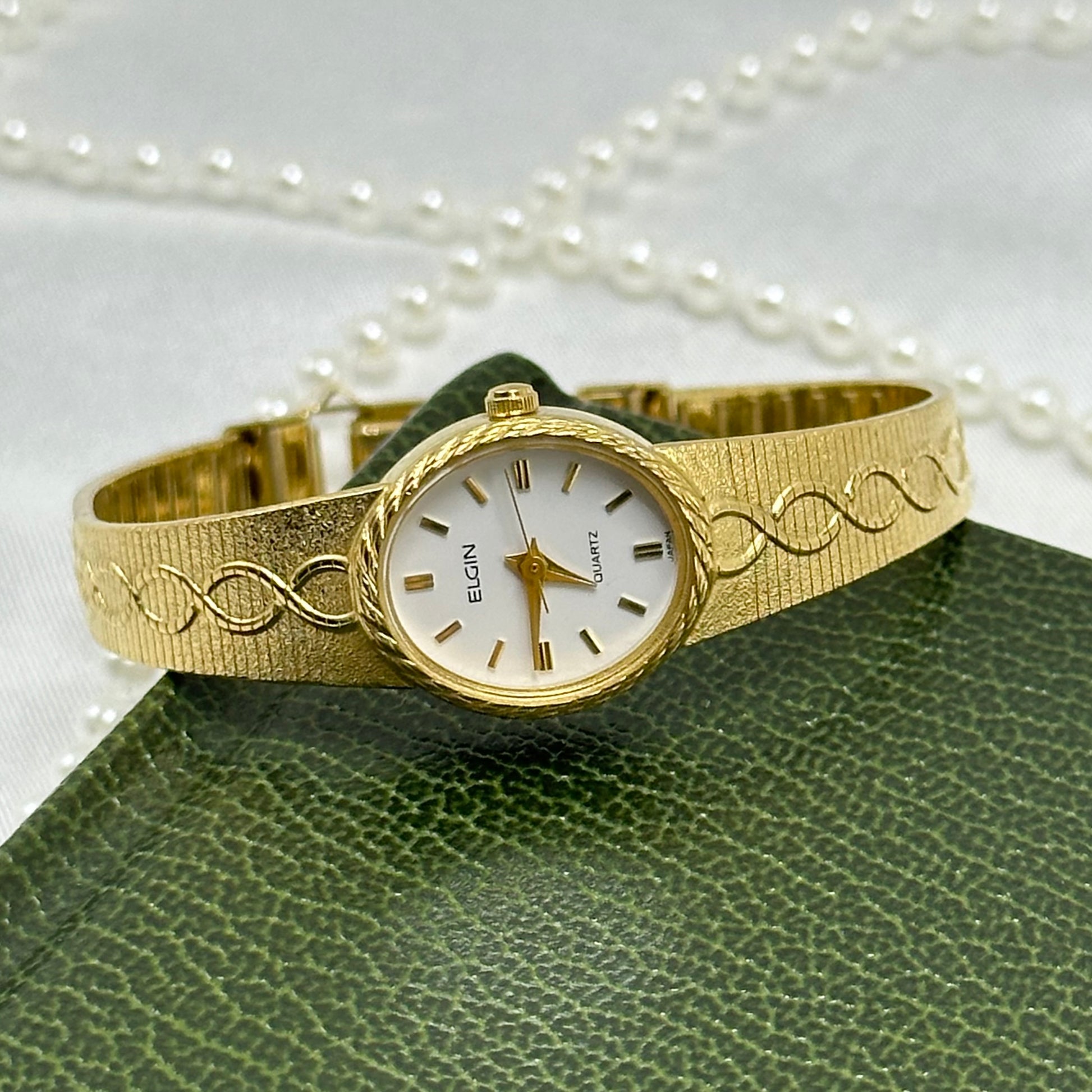 Gold tone vintage Elgin watch with twisted design band and oval dial.