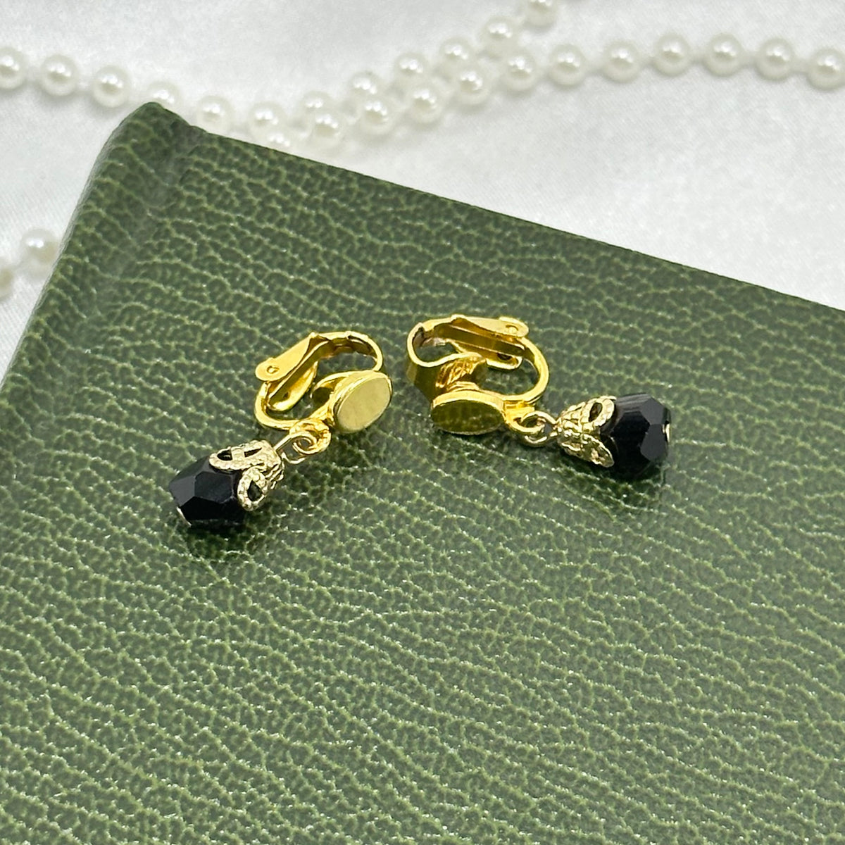 Vintage dangle gold tone clip on earrings with black beads.