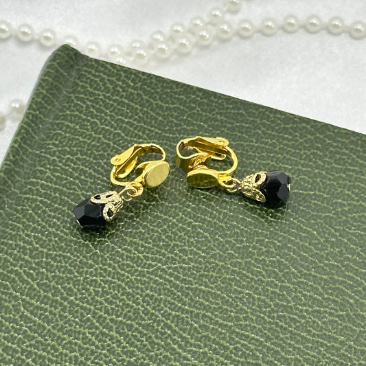 Vintage dangle gold tone clip on earrings with black beads.