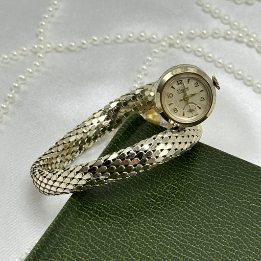 Vintage silver tone manual winding watch with wrap around metal cuff band and engraved back.