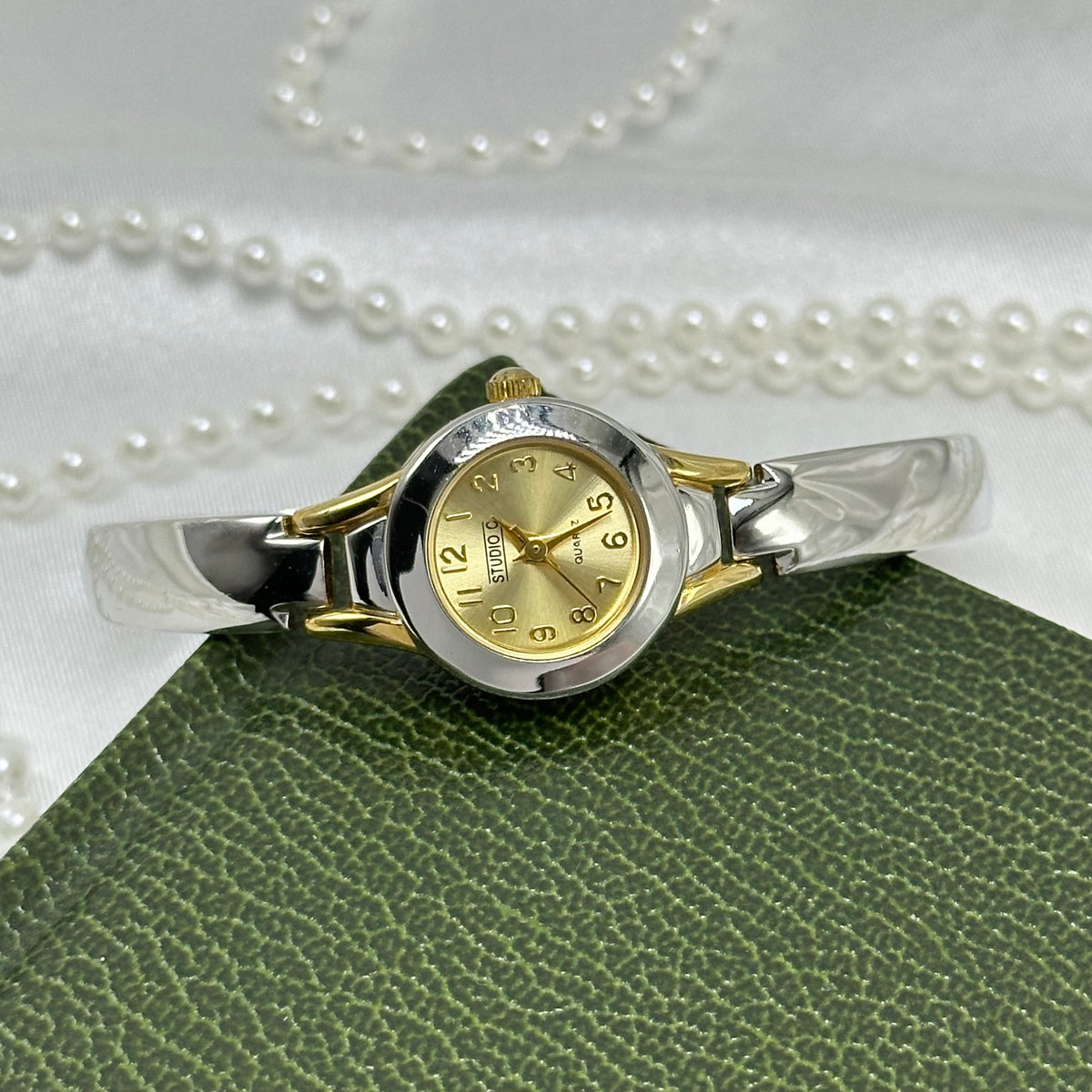 Silver and gold tone Studio C watch with dainty round dial and silver cuff band.