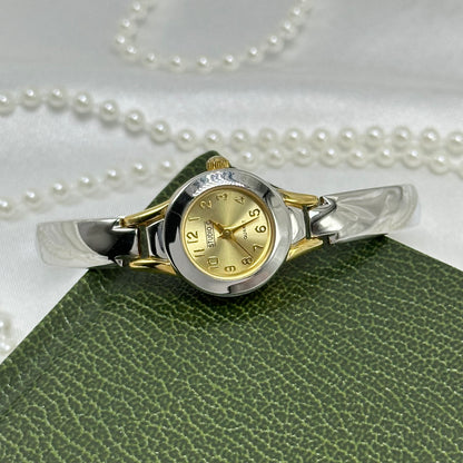 Silver and gold tone Studio C watch with dainty round dial and silver cuff band.