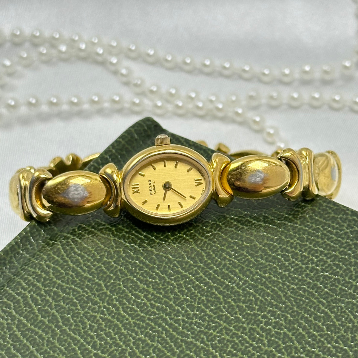 Vintage gold tone Pulsar watch with oval dial, xo "kiss" link band and roman numeral markers from the 1990's.