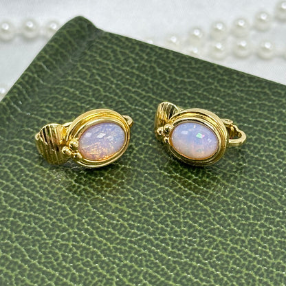Vintage gold tone Avon earrings with oval shaped cabochon faux opal set in a ribbed bezel design from 1989.