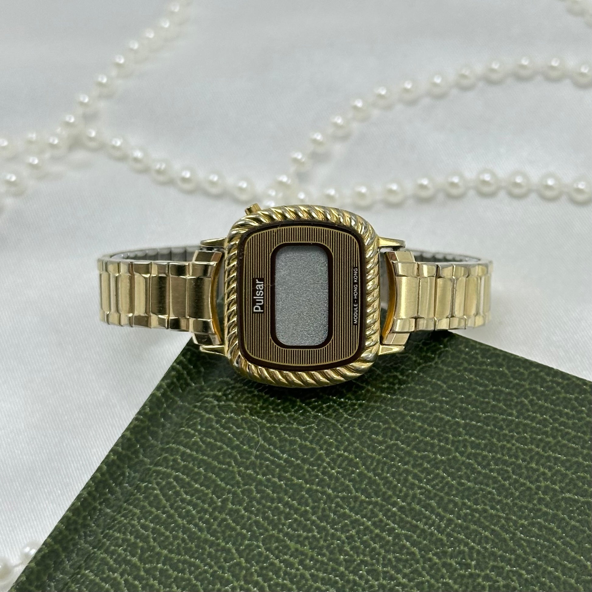 Gold tone Pulsar digital watch with quartz movement and stretchable band.