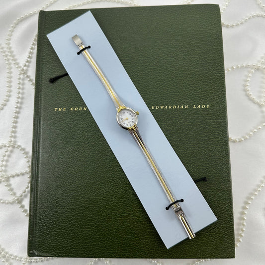 Vintage silver and gold tone Avon watch with oval dial and two-tone metal band. Never worn with original paperwork and packaging.