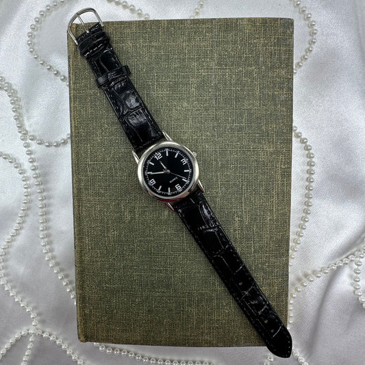 Silver tone watch with black dial and quartz movement.
