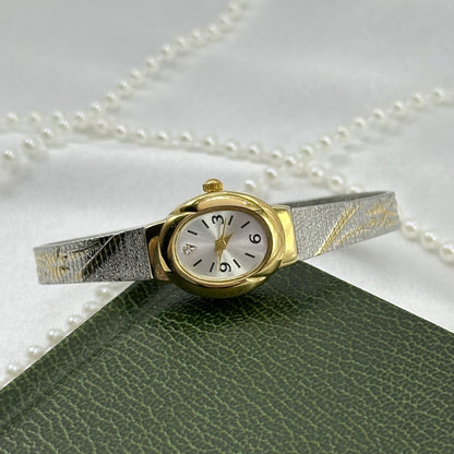 Vintage silver and gold tone Avon watch with two-tone tulip design clasp band and oval dial.
