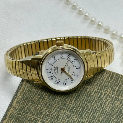 Simple classic gold tone watch with round dial and stretchable band.